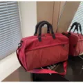 Nahaufnahme der roten Fitness-Reisetasche mit strukturierter Vordertasche und stabilen Griffen. - Große Größe / Burgunderrot