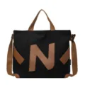 Black canvas tote bag with brown leather accents and a bold letter N design, perfect for use. - Black (Coffee Letters)