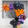 Halloween balloon arch setup detail featuring black, purple and orange latex balloons with spider. - Black and Purple Spider Exploding Star Balloon Garland