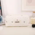 Detailed view of the cute canvas pencil case with bow embroidery and polka dots on a clean desk. - White