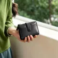 Close-up detail of a classic black folding wallet featuring card slots, snap closure, and zipper. - Black
