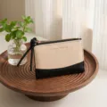 Detail view of the two-tone canvas and leather wallet with wristlet zipper pull in styled scene. - Black