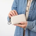 Pochette à clés compacte en cuir texturé avec fermeture éclair et anneau beige. - Blanc