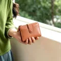 Detail shot of brown leather women fold wallet with card slots and zipper pocket. - Brown