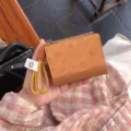 Kοντινό πλάνο καφέ πτυσσόμενου πορτοφολιού με ανάγλυφο σχέδιο ντόνατ και κίτρινο λουράκι καρπού. - Καφέ