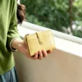 Close-up shot of the yellow mini folding wallet featuring card slots and zipper coin pocket. - Yellow