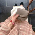 Detailed view of women's taupe leather small saddle coin purse with metal turn-lock closure. - Khaki