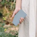 Detailed view of the ultra-thin minimalist two-tone leather wallet in outdoor scene. - Grey Blue