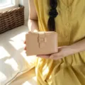 Primo piano del portafoglio bifold beige minimalista con fibbia quadrata in metallo. - Cachi