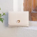 Detail shot of the minimalist tri-fold wallet showing textured leather and gold clasp. - Off White