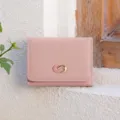 Detail view of a pink minimalist tri-fold wallet with a stylish metal clasp and card slots. - Pink
