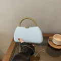Detailed view of light blue hard shell evening clutch bag with unique gold beaded handle. - Box Bag / Blue