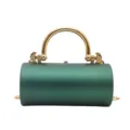 Primo piano di una borsa da sera cilindrica verde scuro con manico e catena in metallo dorato. - Verde