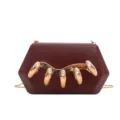 Detail view of maroon acrylic hard clutch featuring sparkling rhinestone gold claw decor. - Burgundy