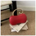 Vista dettagliata della pochette da sera rossa a forma di arachide con elegante manico dorato. - Rosso