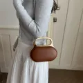 Elegant brown oval handbag with metallic gold handle and chic chain strap for women. - Brown