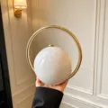 White marble acrylic round evening bag with gold ring handle, elegant handbag detail view. - White