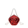 Detailed view of the glossy red acrylic rose clutch handbag with pearl handle and gold chain. - Red Top-Handle Crossbody Bag