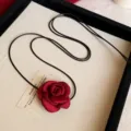 Close-up detail of the elegant red fabric rose pendant necklace with black cord choker style. - S / Red