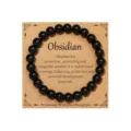 Black obsidian round bead bracelet on display card, natural stone energy jewelry for daily wear. - Obsidian Cleansing Style 33