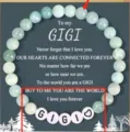 Close-up detail of the handmade beaded stone bracelet featuring custom letter beads and card. - Light Green GIGI