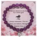 Bracciale di perle viola con ciondolo a cuore argentato su carta di presentazione rosa dettaglio - Con Carta Confezione / Cuore Viola