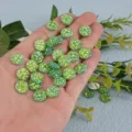 Close-up detail shot of shiny green resin rhinestone flatbacks held in hand for diy crafts. - Light Green