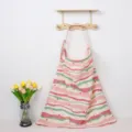 Detail view of printed cotton nursing cover hanging on wall hook with floral decor prop. - Red Striped Rainbow with Iron Clasp