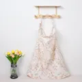 Detailed view of a soft floral cotton nursing cover hanging gracefully on a wooden rack. - Mixed Flower Iron Buckles