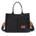 Schwarze Canvas Tote-Bag mit braunen Ledergriffen, Schultergurt sowie praktischen Vordertaschen. - L34 H25 D14 / Schwarz