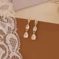 Squisito dettaglio in primo piano di scintillanti orecchini pendenti in zirconia cubica. - Nappa a Tre Pietre / Oro