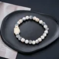 Vue rapprochée de l'élégant bracelet de perles blanches avec de fins détails sculptés de lion. - Bracelet de Perles Texture Lion Blanc (S0055-A)