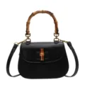 Bolso de montura vintage de cuero negro con asa de bambú natural y correa cruzada elegante. - Negro
