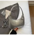 Detailed view of shiny silver patent leather hobo shoulder bag with sleek curved design. - Silver