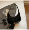 Détail de sac sous les aisselles en cuir verni noir, sac baguette croissant chic. - Noir