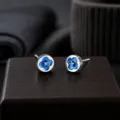 Vue détaillée des boucles d'oreilles clous argentées à fleurs bleues et design unique. - Bleu