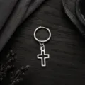 Gros plan détaillé d'une boucle d'oreille créole avec pendentif croix en métal argenté. - Argent