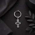 Vue de détail en gros plan d'une boucle d'oreille créole argentée avec pendentif croix. - Argent
