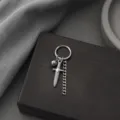 Gros plan détaillé de boucle d'oreille créole argentée punk gothique avec pendentif poignard. - Argent