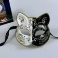 Black and white half face cat mask with gold glitter trim and black ribbon ties for party. - One Size / White & Black