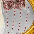 Κοντινό πλάνο διακόσμησης αλυσίδας DIY από ασημί μέταλλο με κόκκινα στραντς και σχέδια. - Ασημί