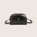 Black wax leather shell crossbody bag with metallic sunburst clasp and white contrast stitching. - Black
