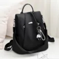 Black casual anti-theft backpack detail shot, stylish black design with bear pendant. - Black