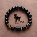 Close-up shot of the black obsidian and tiger eye bead bracelet featuring Aries zodiac design. - Aries