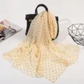 Detail view of a light yellow polka dot silk scarf draped on a chic black handbag for spring. - Small Polka Dot Yellow