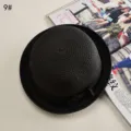 Gros plan sur le détail du chapeau de paille noir avec texture tissée et nœud élégant. - L (58-60cm) / Bord Roulé No.9 / Noir