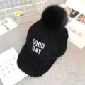 Black corduroy baseball cap detail, warm winter hat with fluffy pom pom and embroidery. - Black