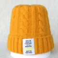 Gros plan sur le bonnet en tricot jaune avec patch de citation blanc et motif torsadé. - Taille unique / Jaune