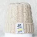 Gros plan d'un bonnet en tricot beige avec un patch de texte citation motivante. - Taille unique / Beige