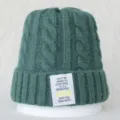Gros plan sur un bonnet en tricot torsadé vert foncé avec patch de texte inspirant. - Taille unique / Vert